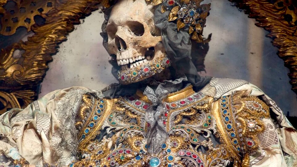 Un squelette de saint martyr vêtu de vêtement orné de bijoux de couleurs variées. 