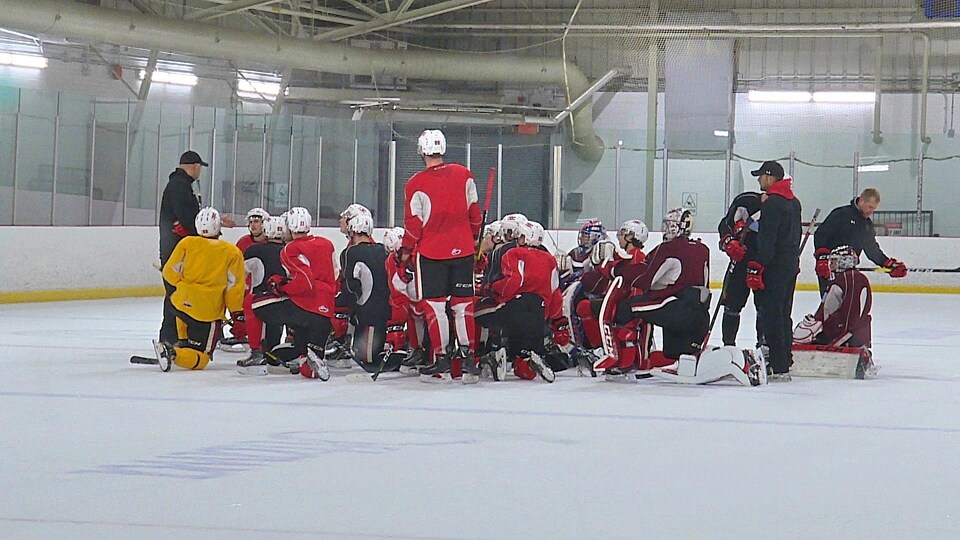 Un groupe de hockeyeurs écoutent leur entraîneur.