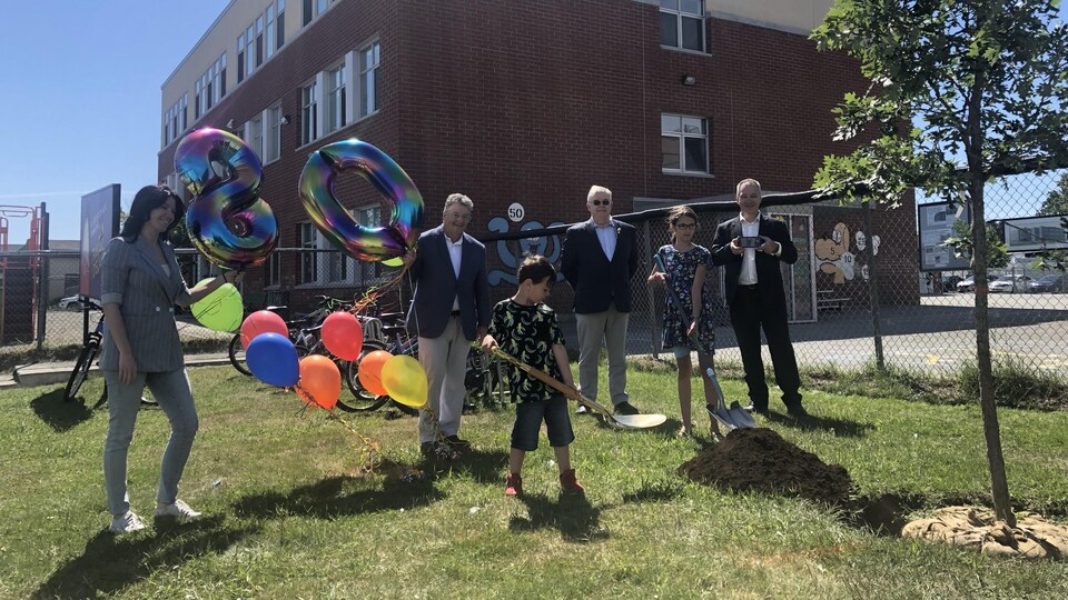 Deux élèves, du personnel de l'école et le maire de Val-d'Or tiennent des ballons ou font une pelletée de terre.