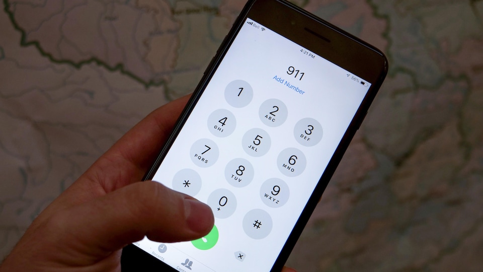 Une main compose le 911 sur un téléphone cellulaire. 