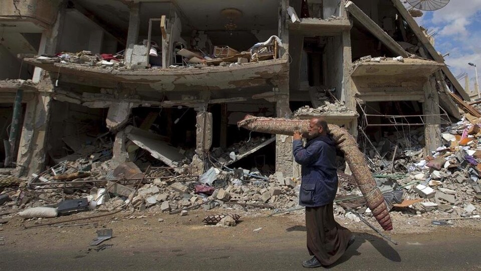Le 14 avril 2016, un Syrien transporte un tapis dans un secteur dévasté de Palmyre, alors que des familles fuient la ville.