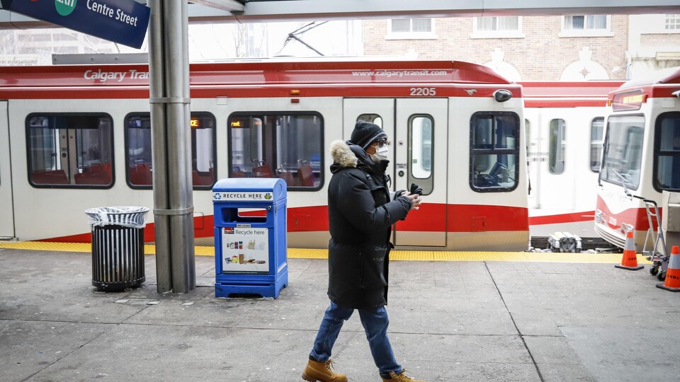 Un homme portant un masque marche sur un quai du C-Train de Calgary pendant la pandémie de COVID-19.