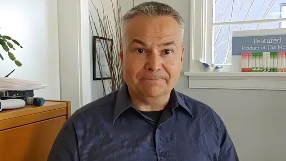 Kevin J. Johnston filmé à la maison, devant une série de livres et une fenêtre.