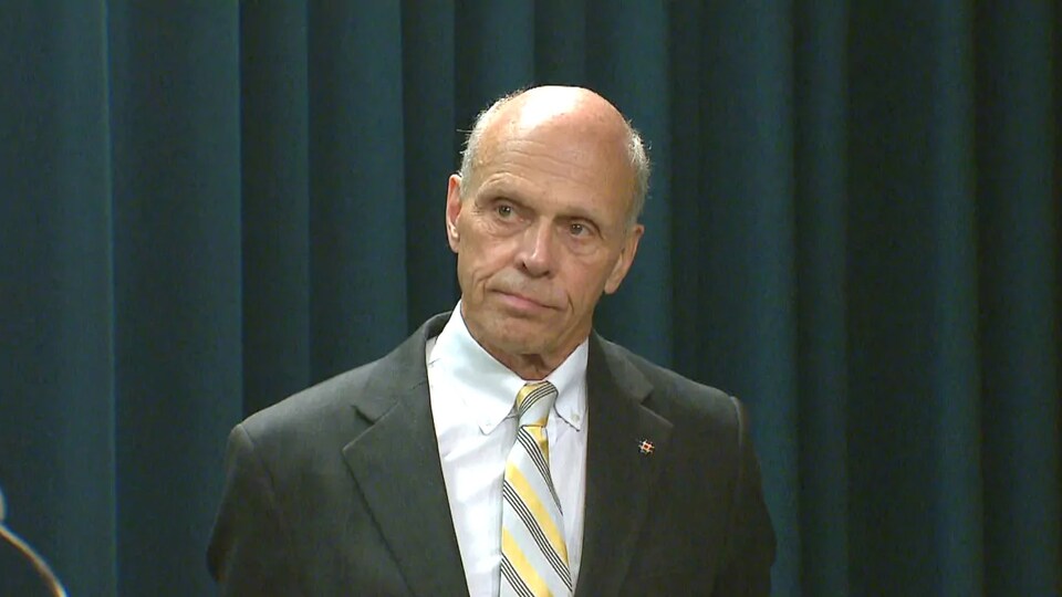 Steve Allan, en conférence de presse devant un rideau noir.