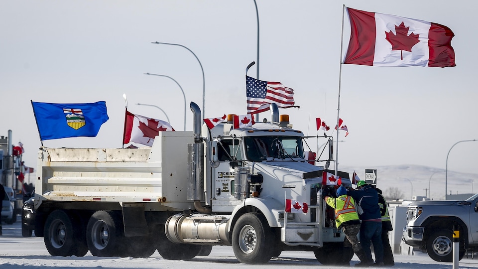 Des personnes déplacent un camion sur les lieux d'une manifestation aux environs du poste frontalier de Coutts, dans le sud de l'Alberta, le 2 février 2022.