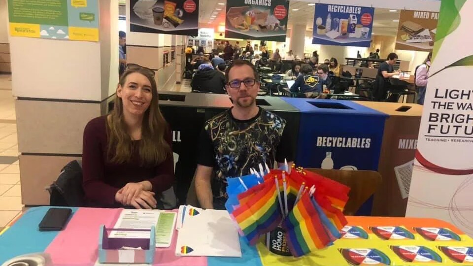 Alex Marshall O (à gauche) est assise derrière une table avec un collègue lors d'un événement de sensibilisation à la réalité des jeunes LGBTQ2+ dans une école albertaine.