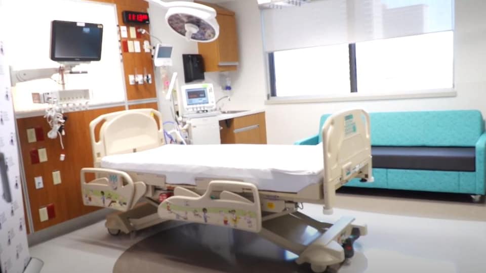 Une chambre de soins intensifs munie d'un canapé, d'un lit d'hôpital et d'équipement médical.
