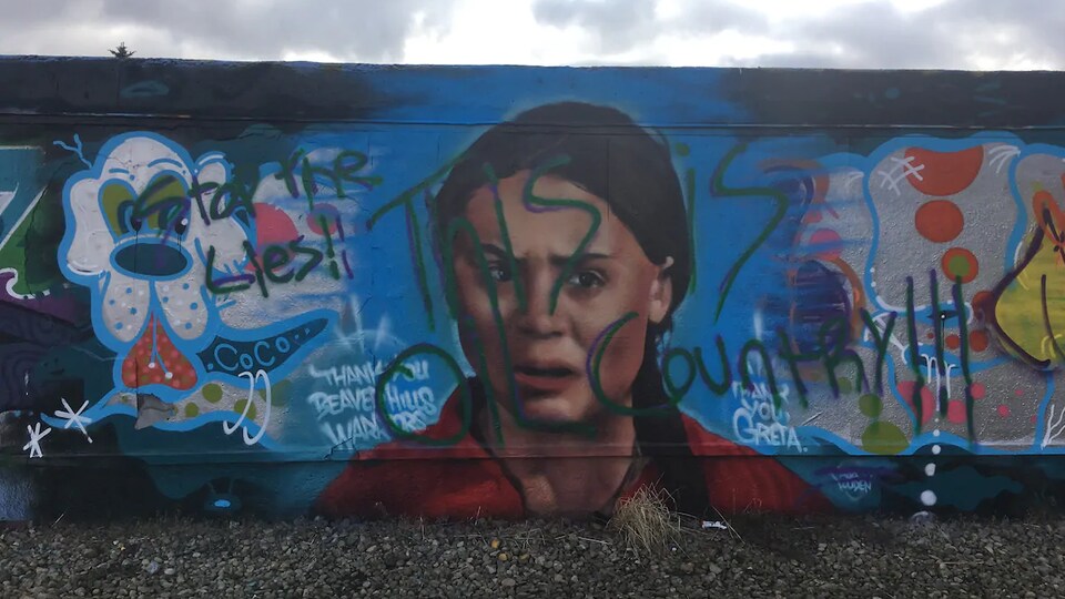 Une murale colorée à l'effigie d'une jeune fille portant la mention « Arrêtez les mensonges. Nous sommes au pays du pétrole », en anglais.