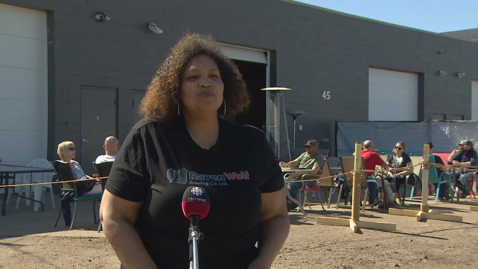 La propriétaire de la microbrasserie RavenWolf, Jan Gillett, répond aux questions d'un journaliste devant la terrasse de son commerce.