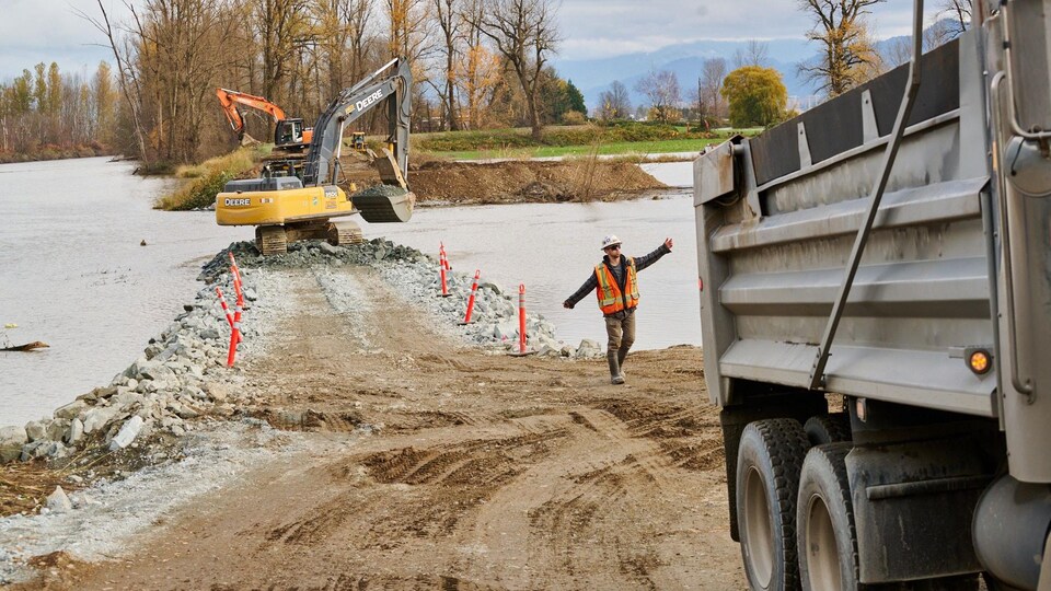 Un ouvrier et des grues au bord d'un champ inondé.