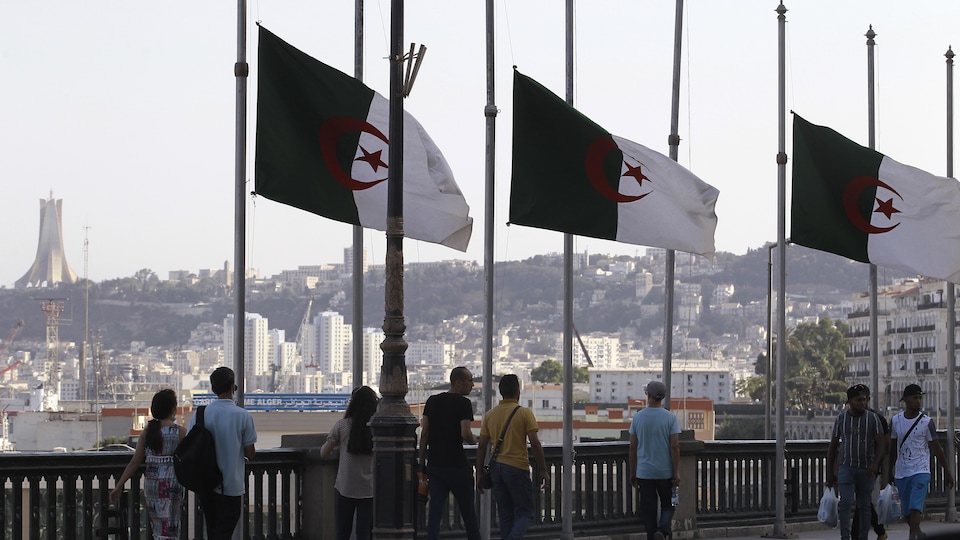 À Alger, des passants croisent des drapeaux de l'Algérie qui sont en berne.