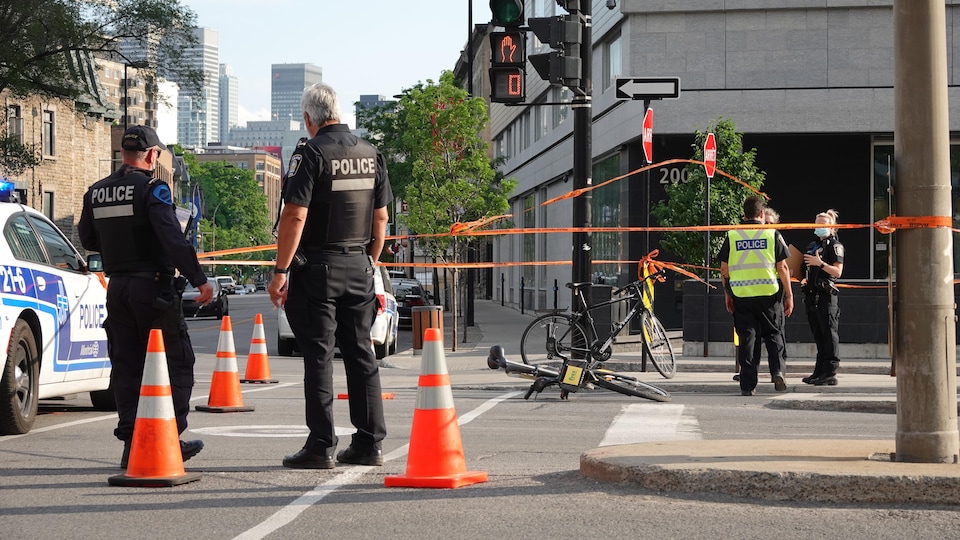 Deux vélos à terre dans une intersection entourés de policiers.