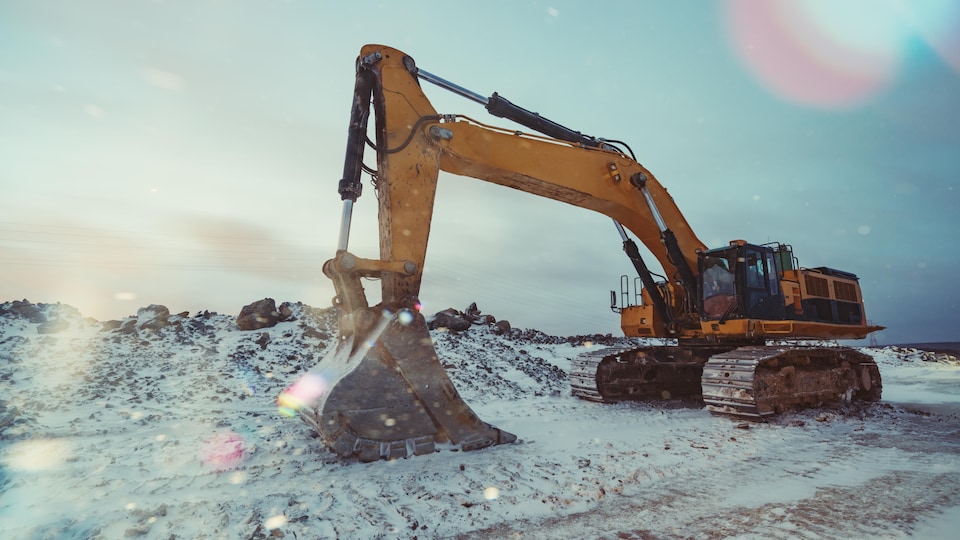 Une machine excavatrice travaillant un sol gelé.
