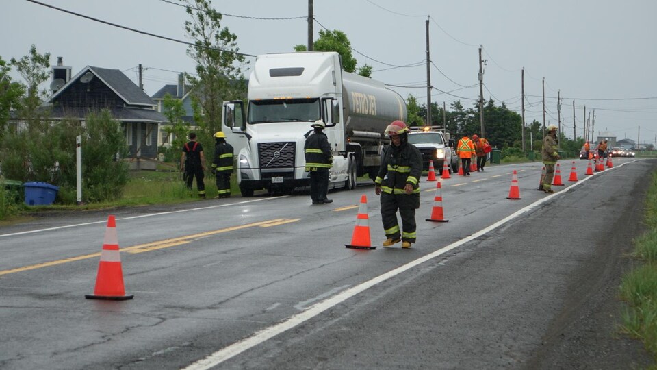 Un camion est arrêté en bordure de la 132 et les policiers observent le terrain.