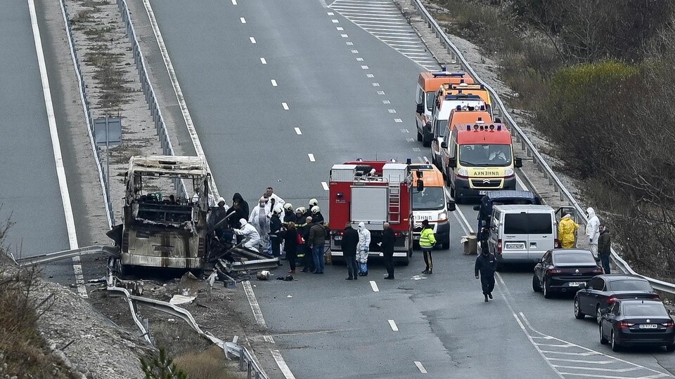 Policiers et pompiers sur le site d'un accident, où un autocar a pris feu.