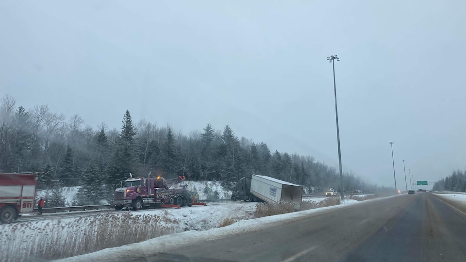 Un camion se trouve dans un fossé à la suite d'un accident sur une autoroute l'hiver. 