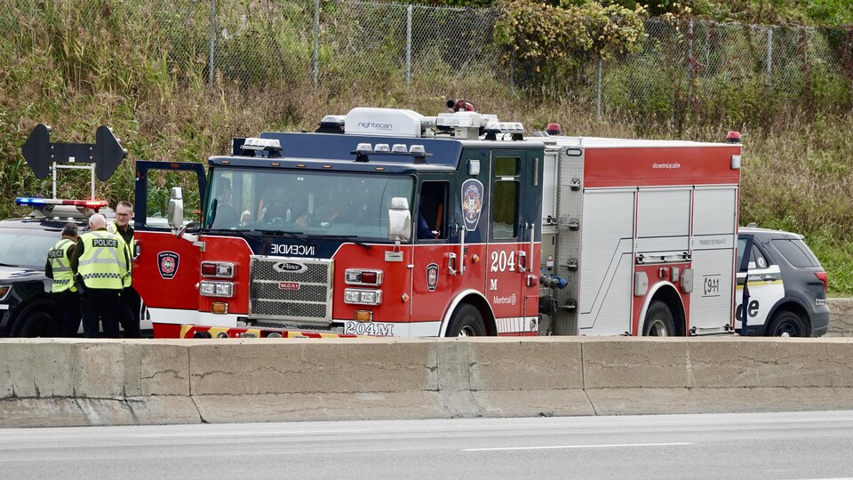 Une camion de pompier immobilisé près d'un muret de ciment sur une autoroute.                   