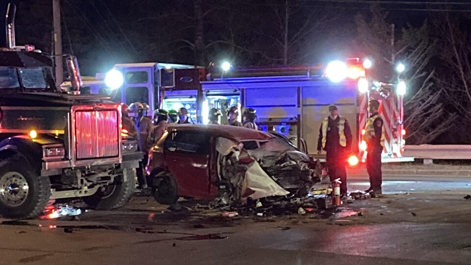 Une voiture accidentée se trouve devant un camion semi-remorque.