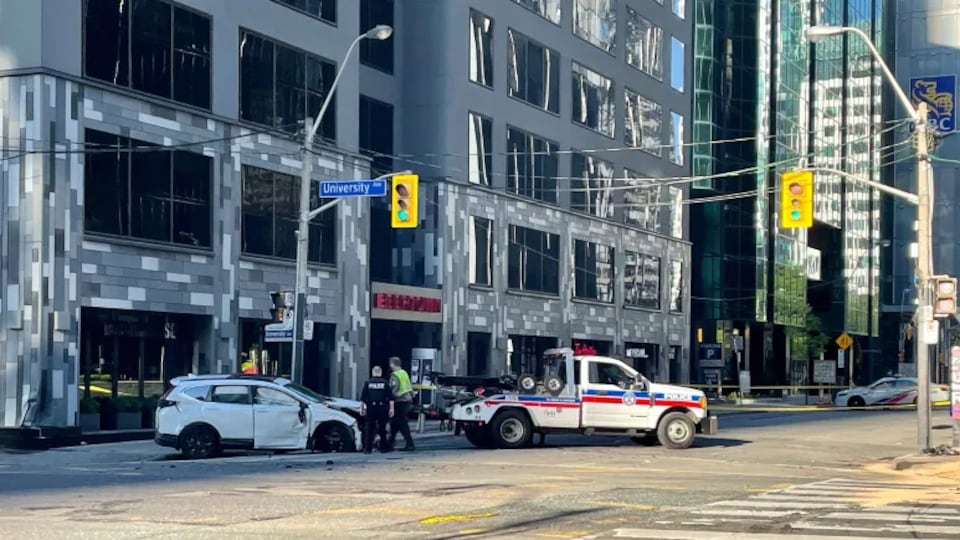 Une scène de l'accident à l'intersection des avenues Wellington Ouest et University. Des policiers circulent autour d'une des voitures endommagées.