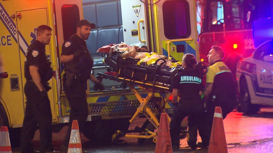 Des ambulanciers placent la civière du blessé dans leur ambulance.