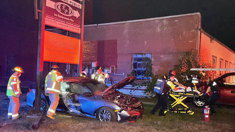 Une voiture endommagée et une personne sur une civière.