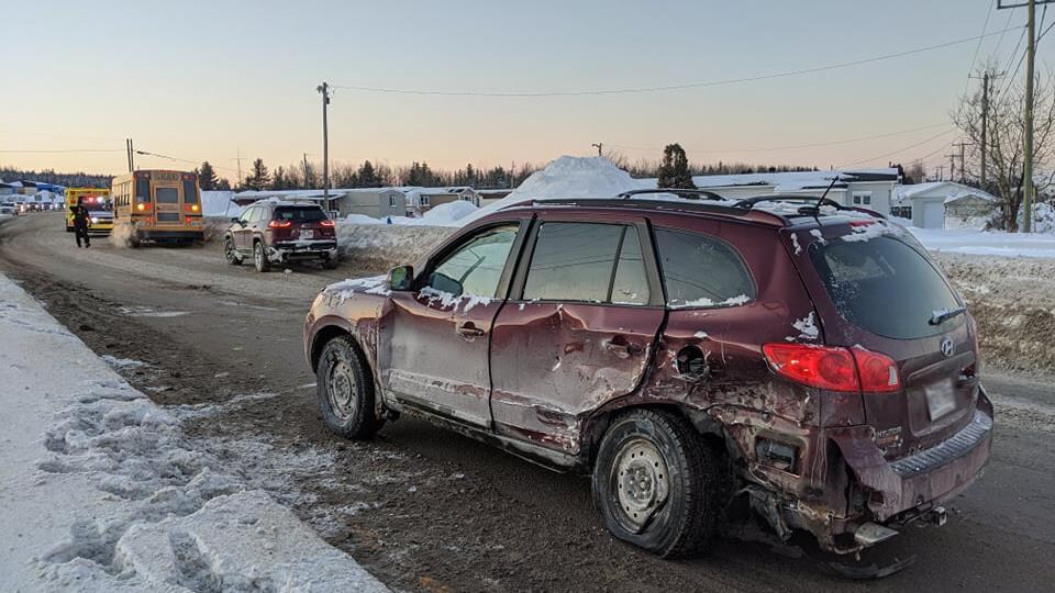 Une voiture accidentée au premier plan devant d'autres voitures l'hiver.