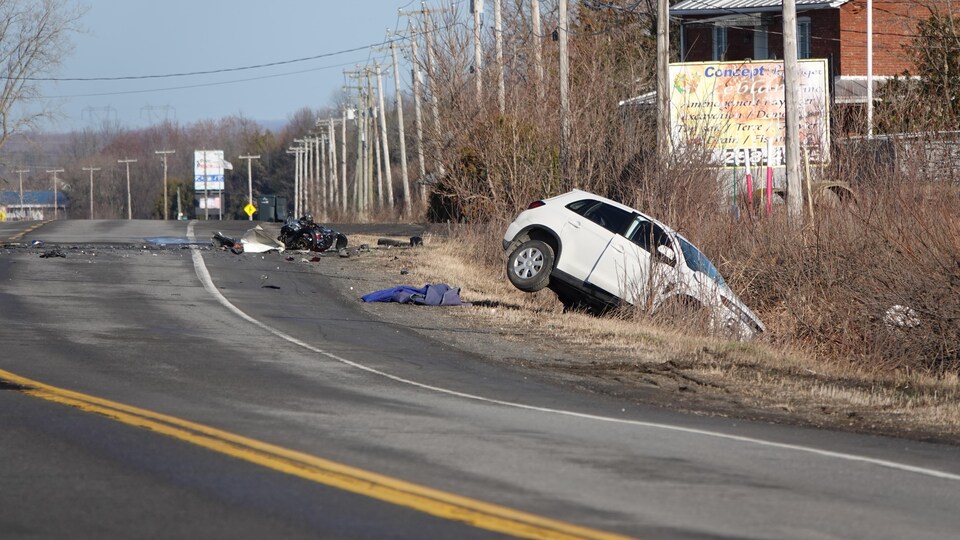 The scene of the accident, showing a car in a ditch and debris from a vehicle.