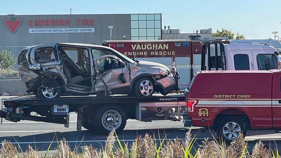 La minifourgonnette accidentée complètement détruite à l'arrière sur la plateforme d'une remorqueuse.
