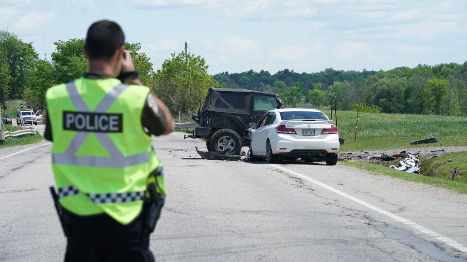 Un policier prend une photo des deux voitures impliquées dans la collision.