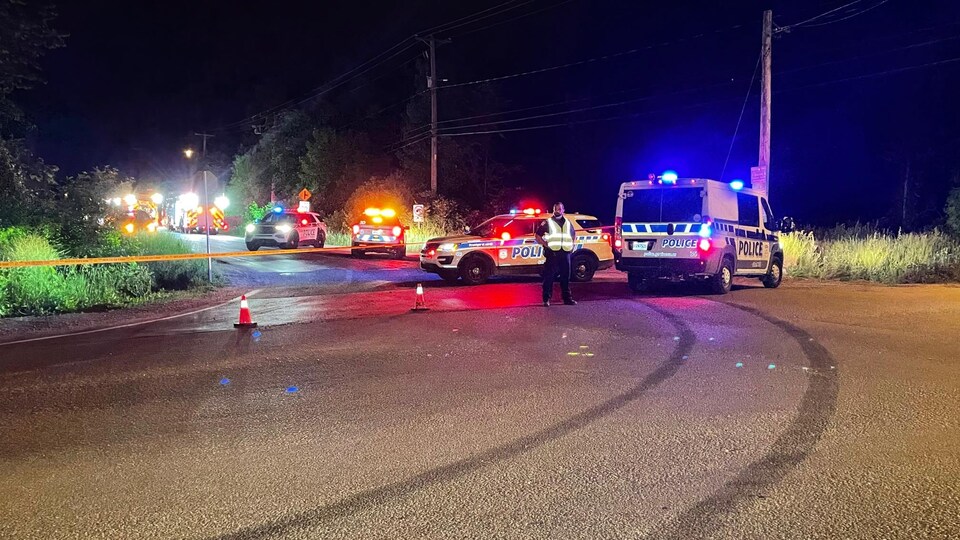 Plusieurs véhicules du service de police, sur une rue la nuit.