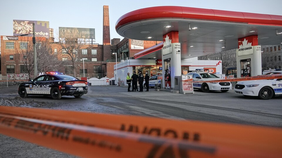 Des voitures de police stationnées dans une station service de Montréal.