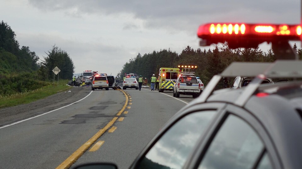 Gyrophares avec voitures accidentées et voiture de police au loin.