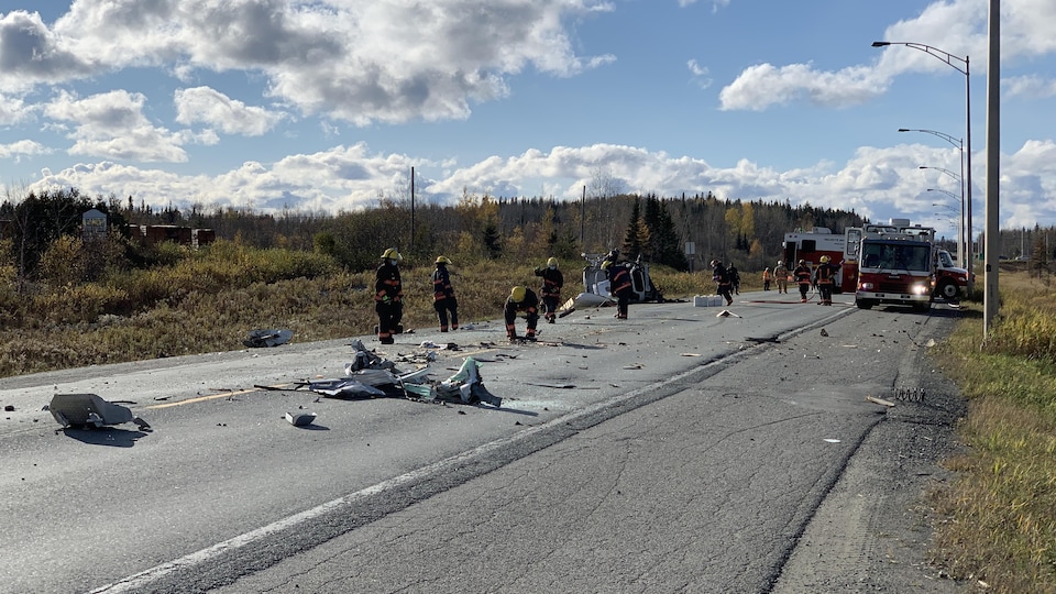 Des pompiers ramassent des débris sur la route sur le site d'un accident.