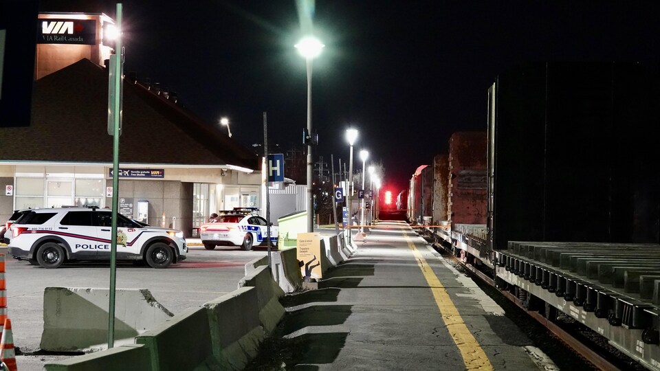 Several police vehicles were parked near the railroad tracks. 