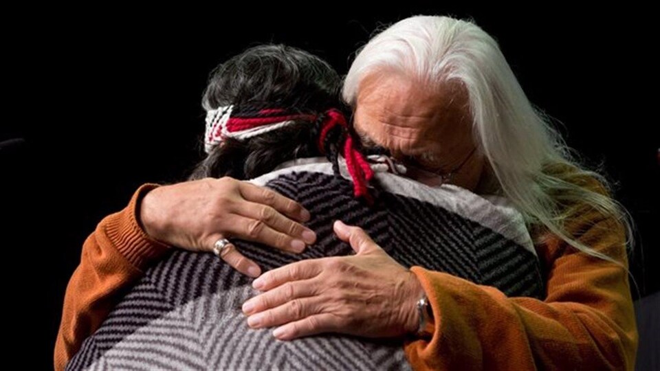 Deux survivants des pensionnats autochtones s'étreignent lors d'un événement de la Commission de vérité et réconciliation du Canada à Vancouver.