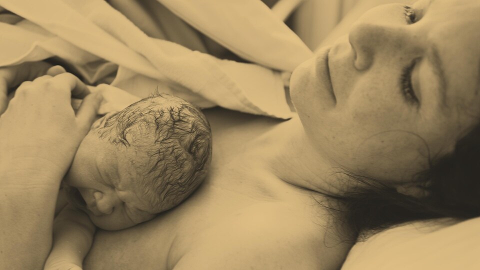 Un nouveau-né couché sur une mère épuisée, mais calme et heureuse.