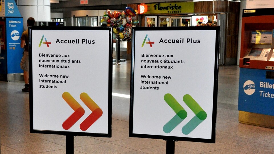 Deux affiches à l'aéroport Pierre-Elliott-Trudeau de Montréal indiquent avec des flèches pointant à droite: "Accueil Plus, Bienvenue aux nouveaux étudiants internationaux" et ce, en français et en anglais.