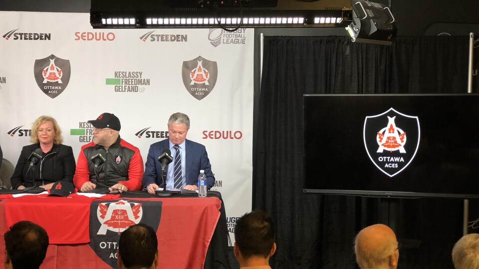 Des gens assis à un podium pendant une conférence de presse des Aces d'Ottawa.