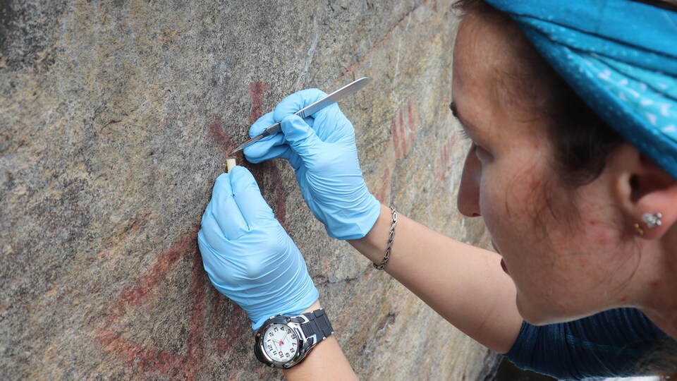 Une femme qui fait une oeuvre sur la pierre.