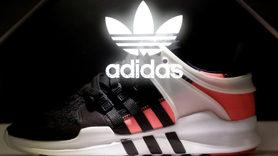 Le logo d’Adidas, illuminé et apposé au-dessus d’une chaussure de sport, un montage photo fait pour l’assemblée annuelle des actionnaires de cette entreprise en Allemagne, le 11 mai 2017