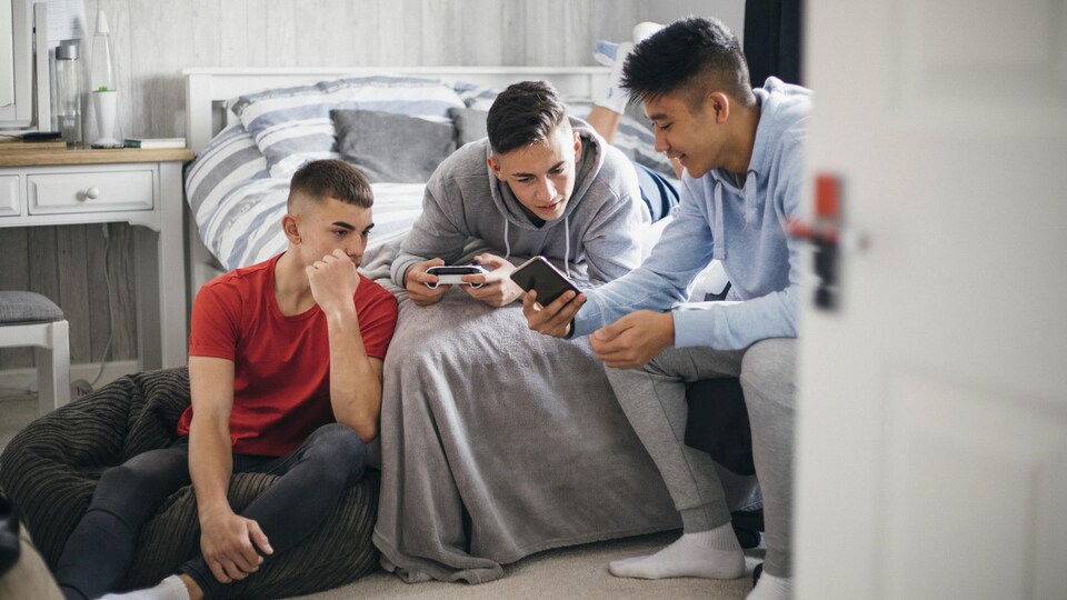 Trois adolescents s'amusent avec des appareils électroniques.