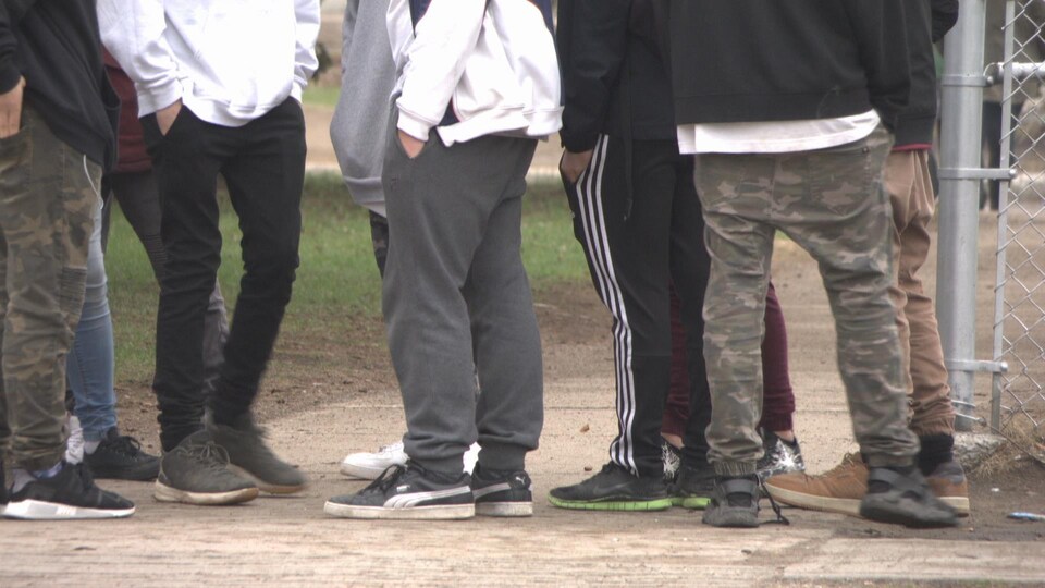 Les jambes d'adolescents devant une cour d'école.