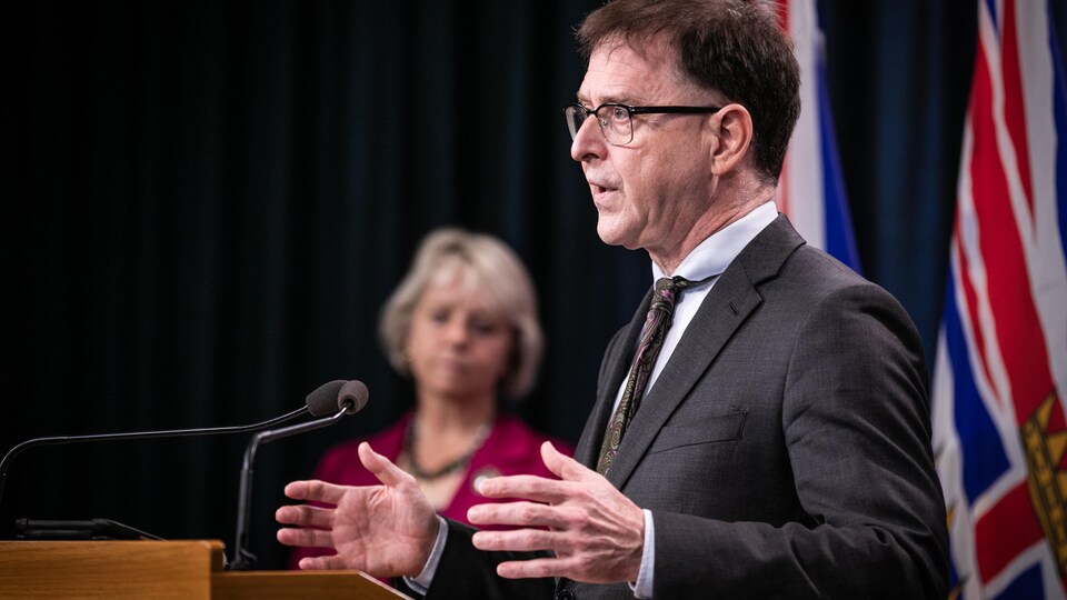 Adrian Dix sur une estrade, devant Bonnie Henry.