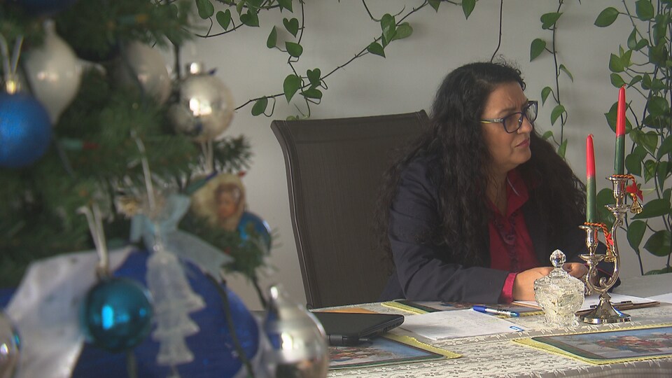 Adrianna Herrera est assise à une table, entourée de décorations de Noël.