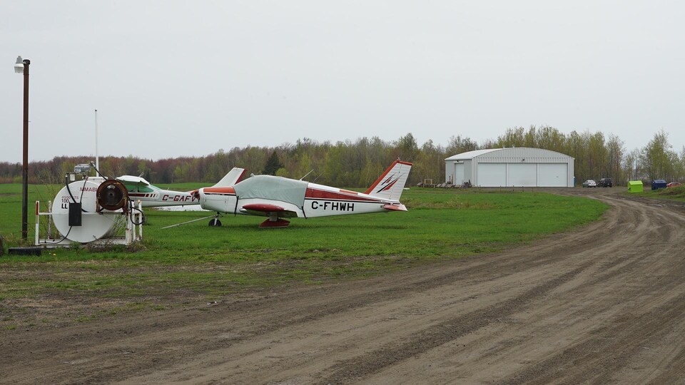 Deux petits avions stationnés à proximité d’un hangar à l’aérodrome de Pintendre