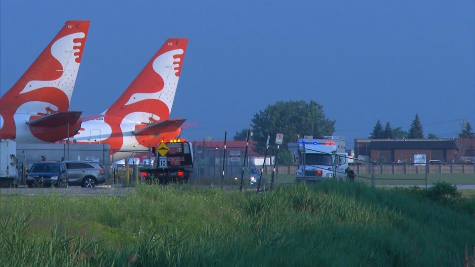 Des véhicules de police près d'un tarmac d'avions.