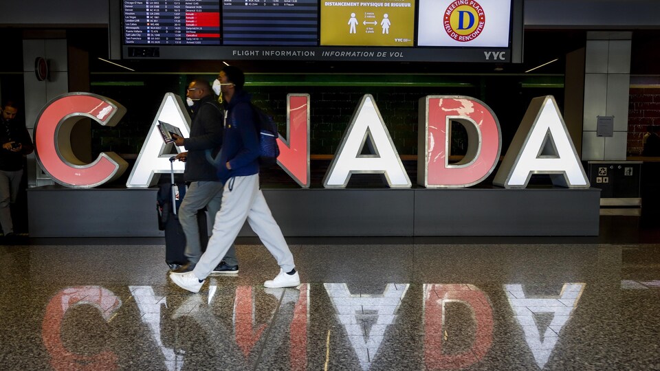 Deux hommes marchent dans un couloir de l’Aéroport de Calgary. 