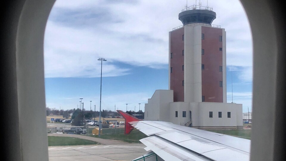 La tour de contrôle de l'aéroport photographié par le hublot d'un avion.