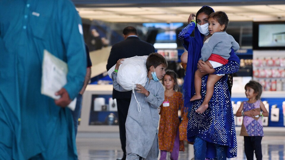Une femme et ses enfants dans le hall d'un aéroport.