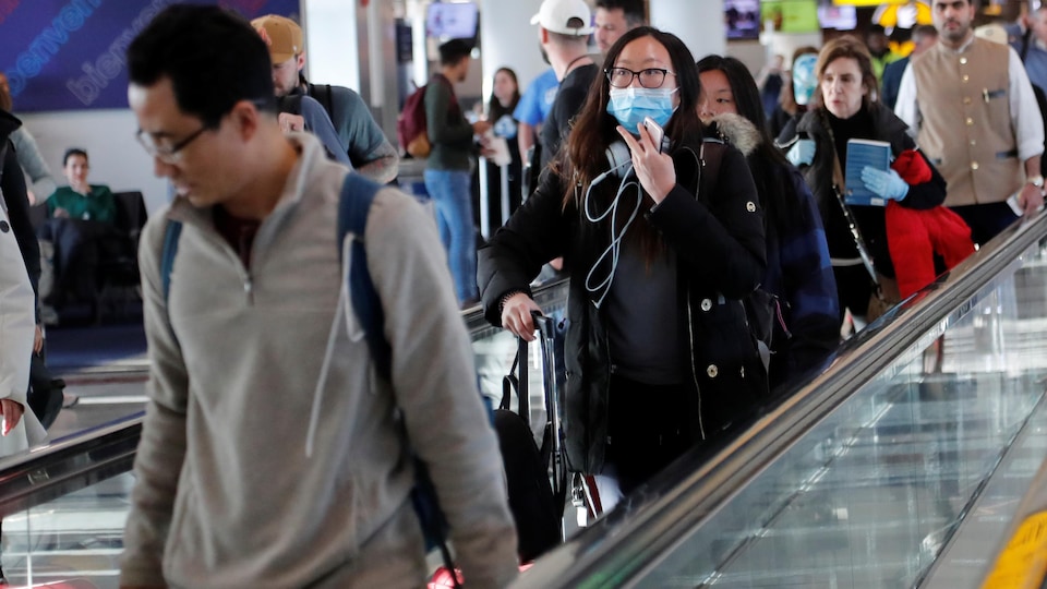 Une femme porte un masque protecteur dans les corridors d'un aéroport new-yorkais.
